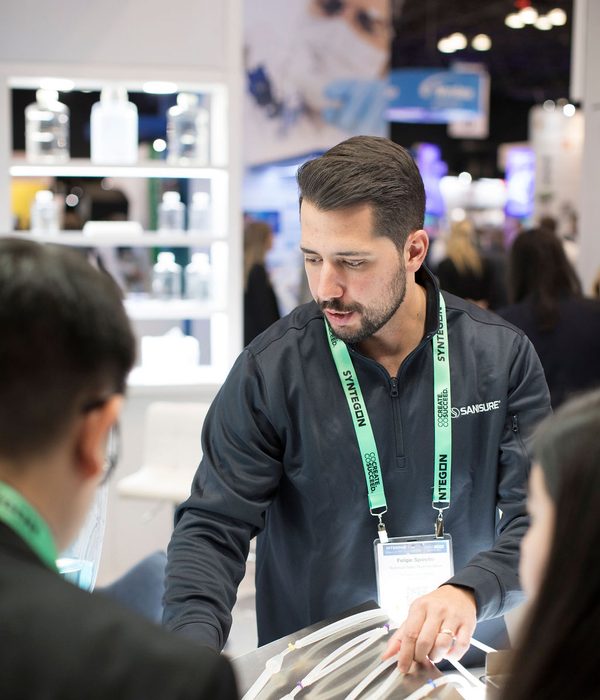 SaniSure representative presenting single-use fluid path assembly to attendees at a trade show