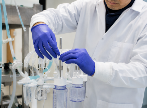 Bioprocessing technician in cleanroom configuring a custom single-use fluid management assembly with multi-port tubing and connector components on a stainless steel rack