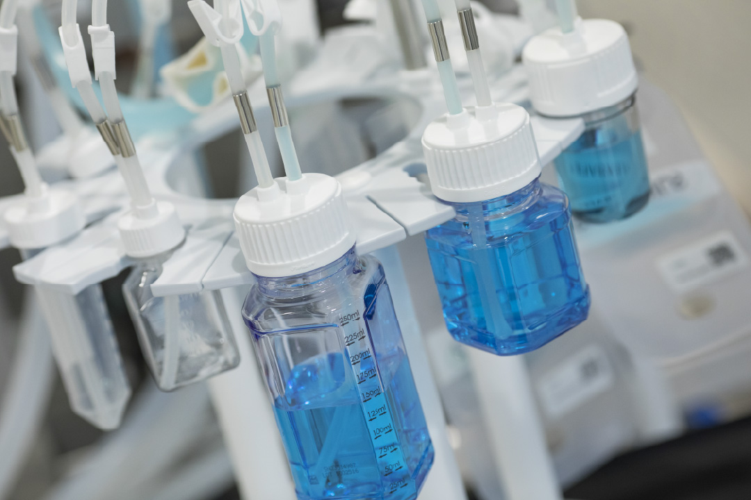 Close-up of gloved hands connecting tubing to a SaniSure one2sample single-use container for bioprocessing fluid sampling